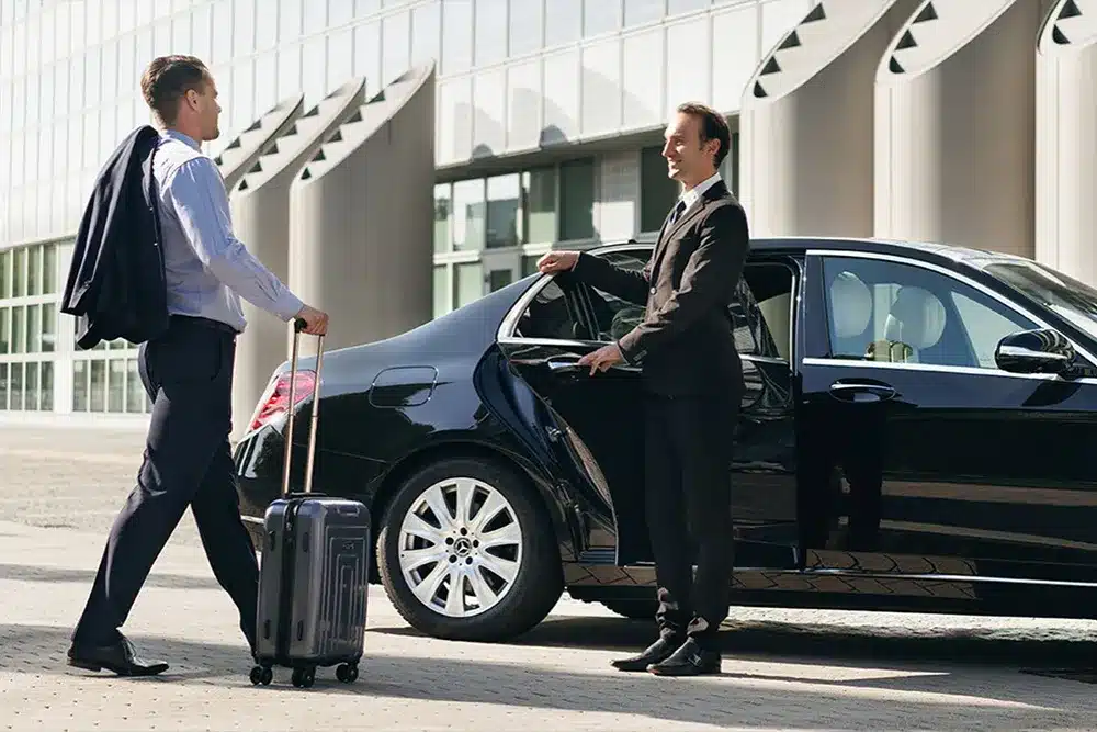A premium chauffeur waiting at a London hotel kerb with an executive Mercedes