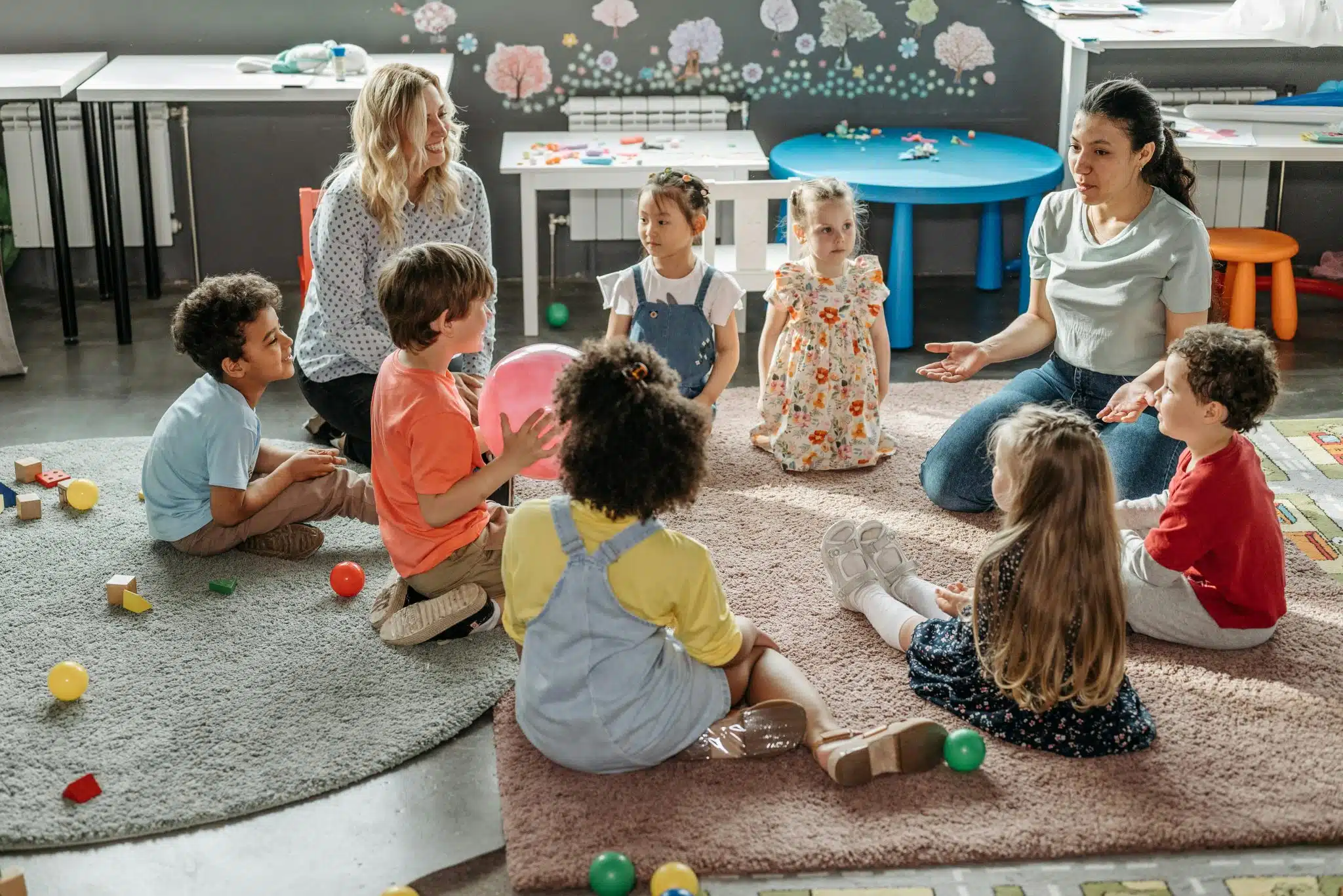 Nursery practitioners with a circle of young children during a UK early-years session